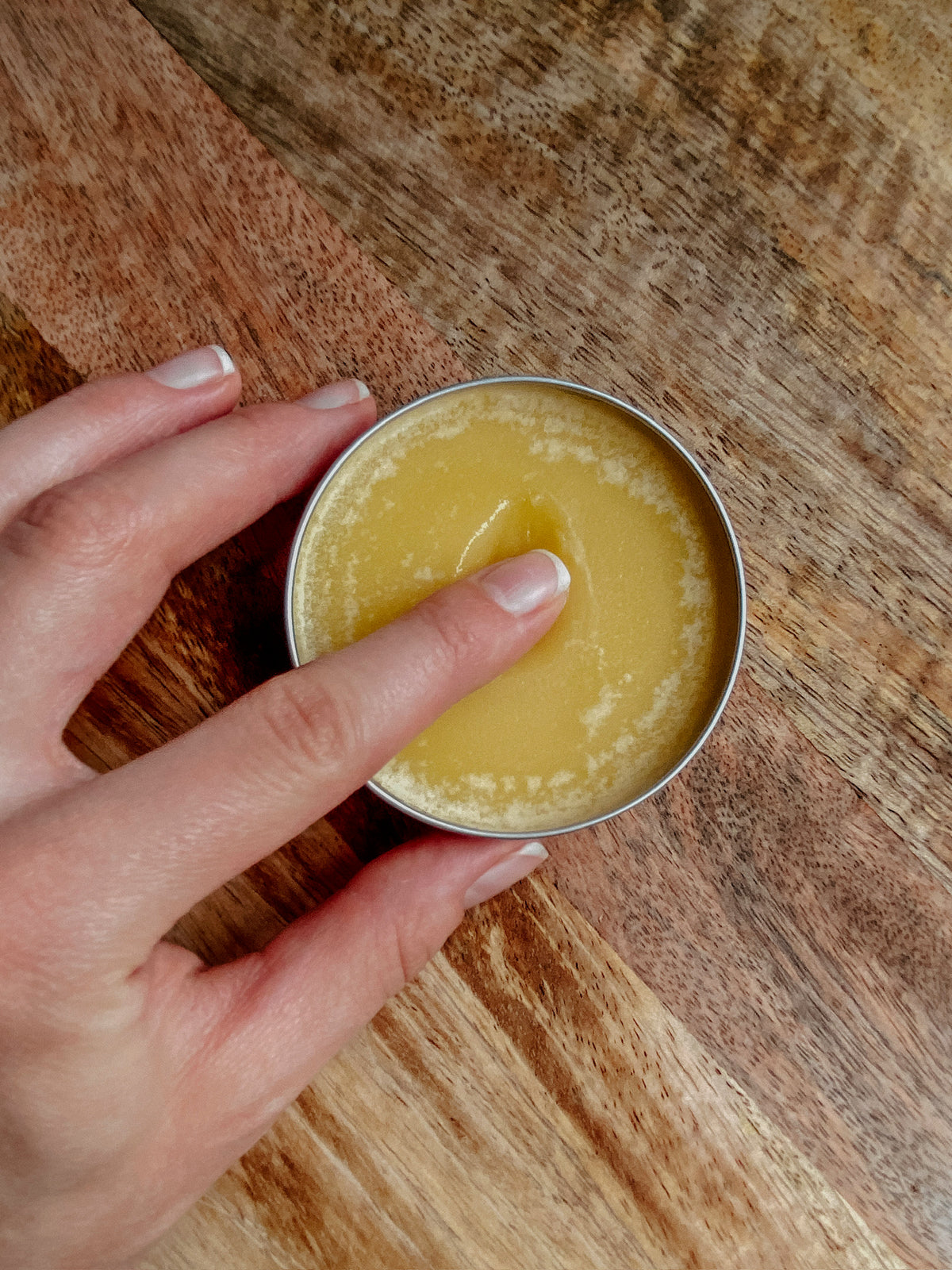 Soothe Hand & Body Salve 2.5 oz tin, open, held in hand