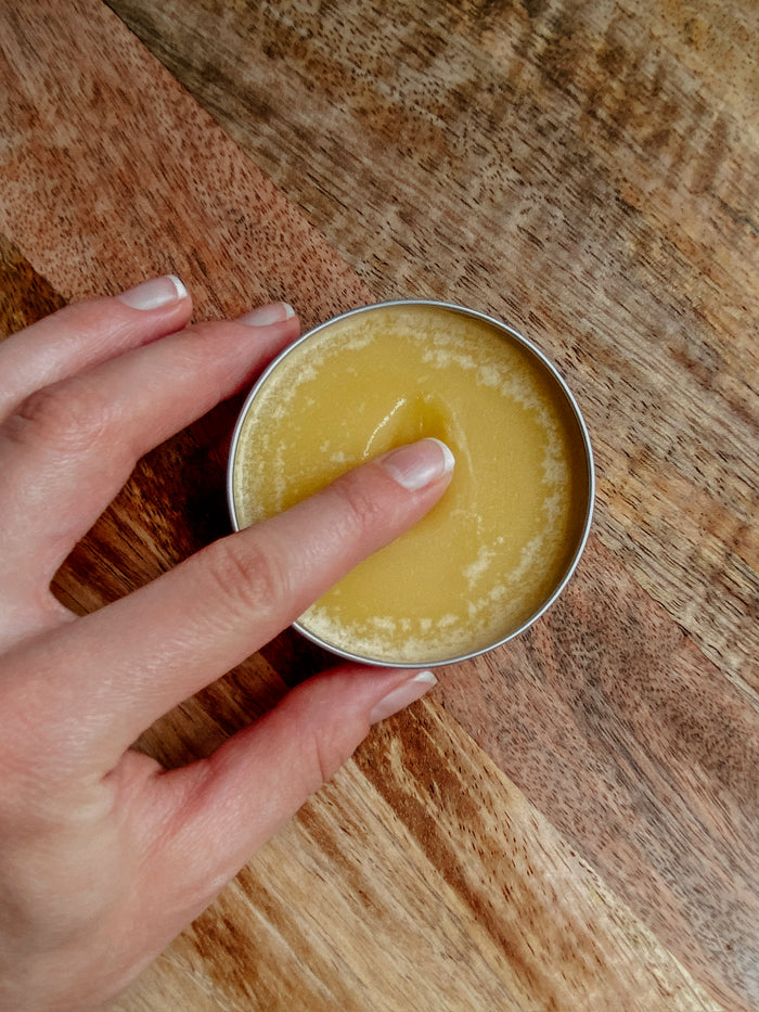 Soothe Hand & Body Salve 2.5 oz tin, open, held in hand
