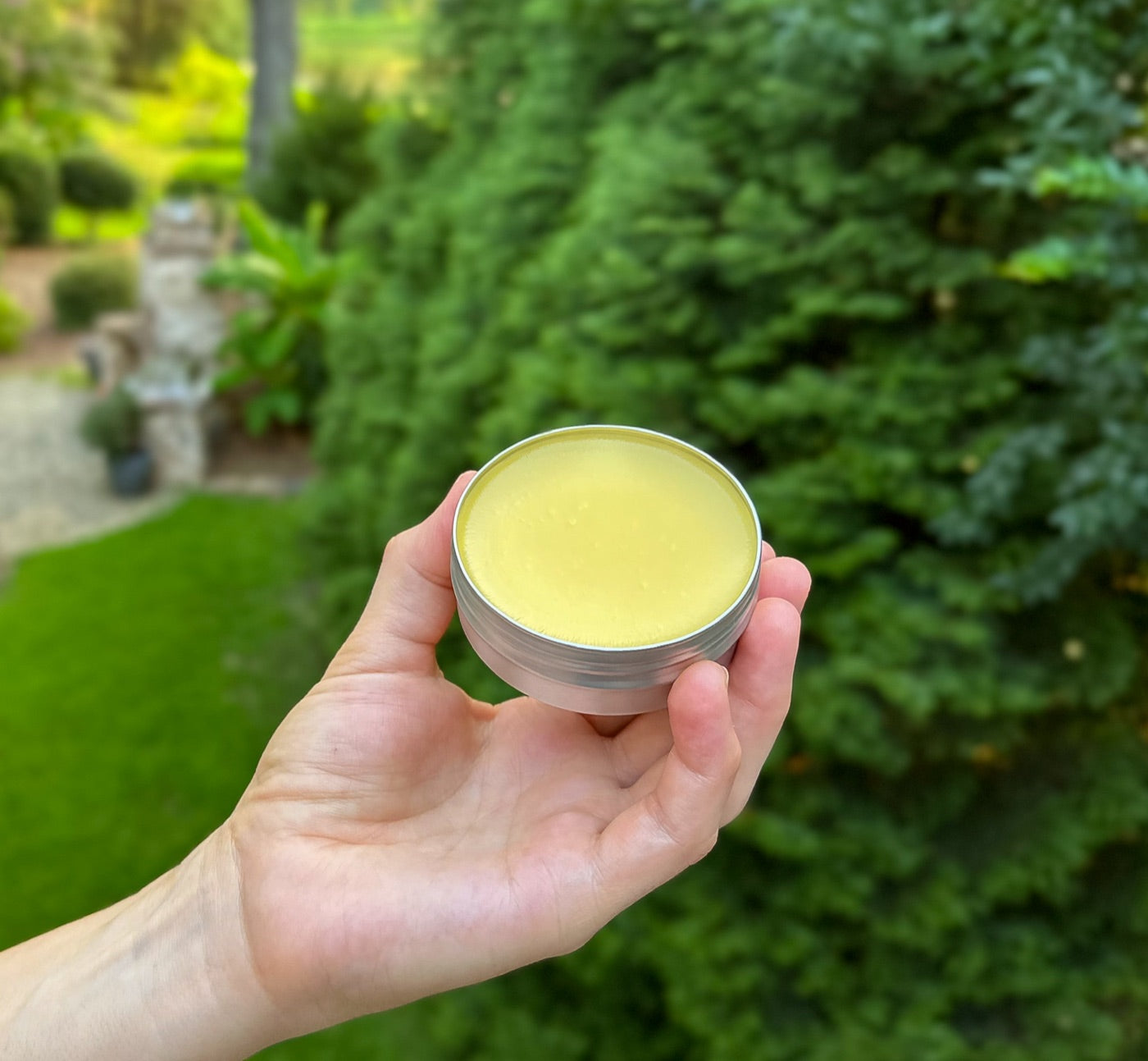 A baby's hand reaching for an open tin of Soothe Salve on a wooden floor
